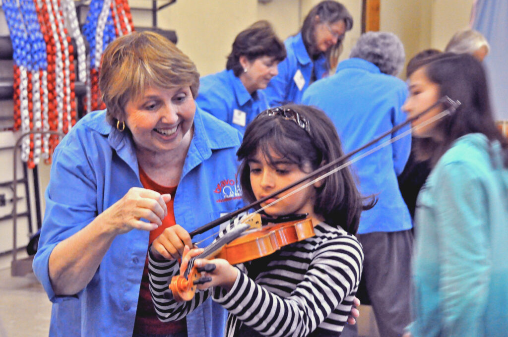 OFWC Member helping student play violin