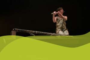 Flutist Claire Chase sitting on floor playing instrument