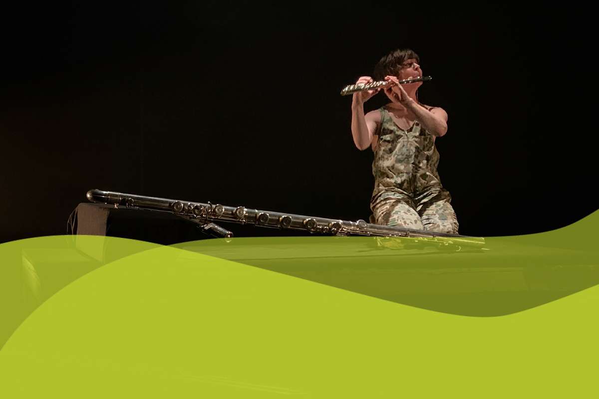 Flutist Claire Chase sitting on floor playing instrument